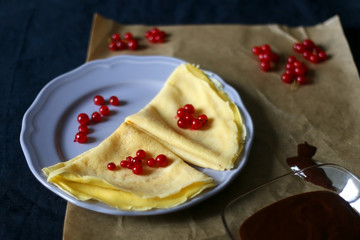 Homemade crepes with chocolate spread and red currants. Selective focus.