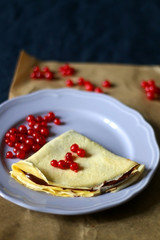 Homemade crepes with chocolate spread and red currants. Selective focus.