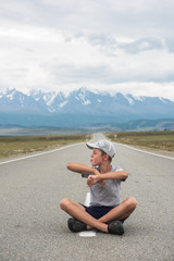 Fototapeta na wymiar Young boy sitting on the beauty road in mountain