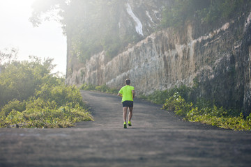 Man jogging on a downhill / uphill in suburb mountain road.