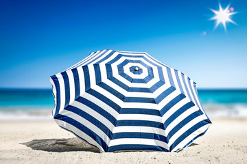 Summer time on beach and free space for your decoration. Blue and white umbrella with landscape of...