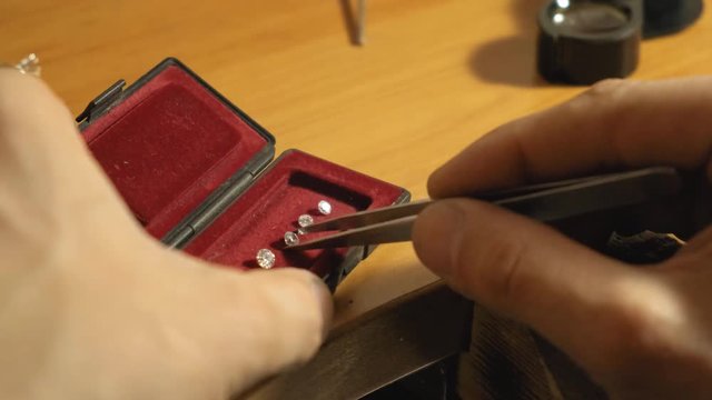 Goldsmith takes the jewel stone from the red box with the pincette slow motion