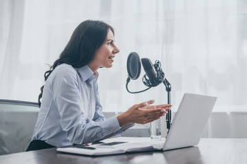 smiling radio host gesturing while recording podcast in radio studio