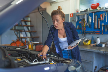 Making some adjustments to her car. Portrait of young female mechanic. Female mechanic fixing car.. Auto car repair service center. Repair, car service concept