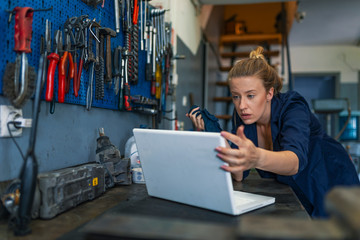 Mechanic working on a laptop. Female garage mechanic conducting diagnostic check. Female mechanic with laptop. Auto car repair service center. Repair, car service concept