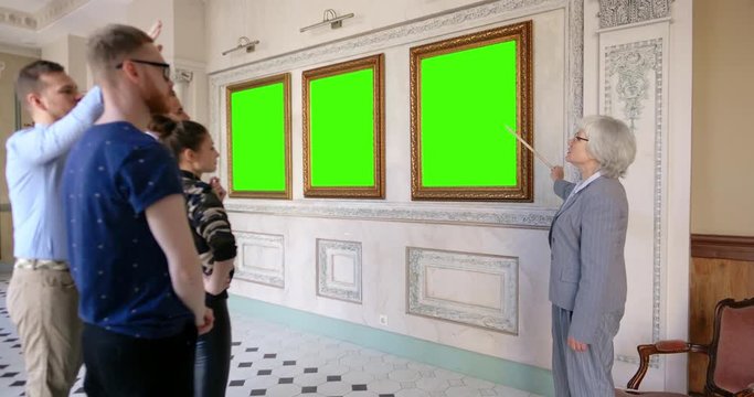 Museum visitors taking tour with guide and looking pictures