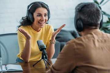 selective focus of excited radio host gesturing while looking at colleague in radio studio