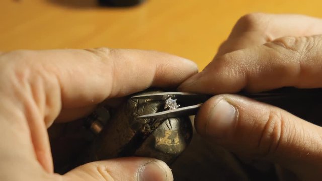 Manual fixing the crown with the gemstone using tweezers sloiw motion