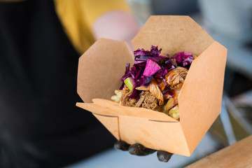 Man serving a chicken kebab with chips in a box at a Street food festival