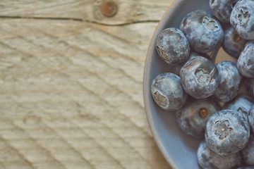 Top view of bowl with blueberries on wooden table. Copy space for your text