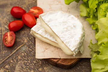Delicious white mold cheese with vegetables on a cutting board. Snack to wine with copy space