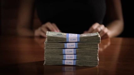 Sexy woman pushes a stack of money accross a table. - Powered by Adobe