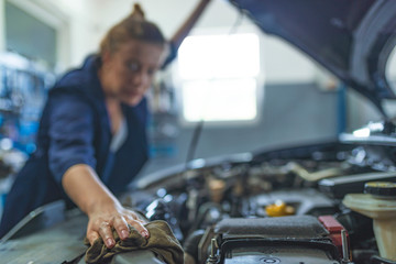 Female Auto mechanic working in garage. Repair service. Woman with dirty hands fixing the car. Getting her car back on the road. Mechanic working in his workshop