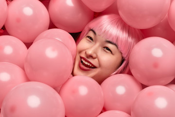 Fototapeta na wymiar Cheerful Asian female in heap of balloons