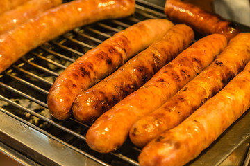 Grilling pork sausages on barbecue grill closeup view