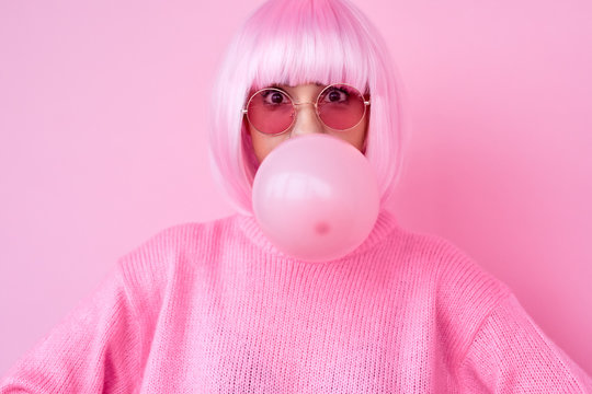 Young Woman In Pink Outfit Blowing Gum