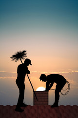 chimney sweep on the roof at sunset