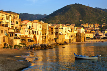 Beautiful old harbor at sunset with wooden fishing boat, Cefalu, Sicily, Italy