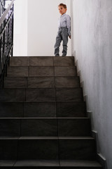 child alone on top of a dark staircase