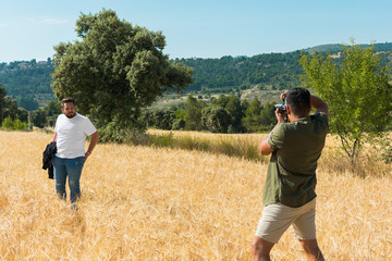 Naklejka na ściany i meble Photographer doing a photo shoot in a field to a model