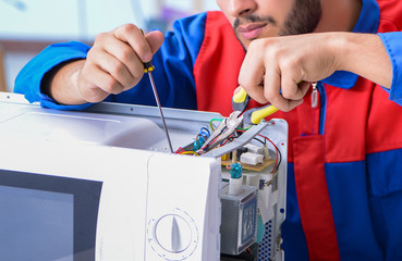 Young repairman fixing and repairing microwave oven