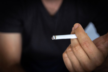 Man holding a cigarette, closeup cigarette and hand. Bad habits.