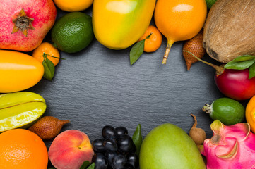 Exotic tropical fruits on black textured stone background, healthy food, vegetarian diet