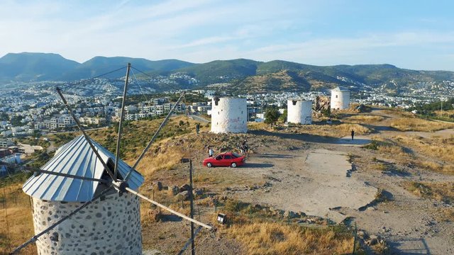 Old windmills in Bodrum. Group of friends taking photos on the background. Welcome to Turkey concept 4k