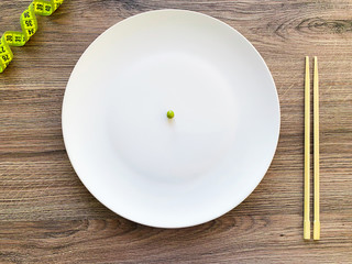 Cropped image pea on white plate, with fork and measuring