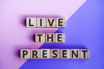 phrase live the present, wooden cubes with letters on color background top view
