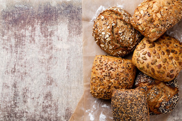 Gold rustic crusty loaves of bread and buns on wooden background. Still life captured from above top view, flat lay.