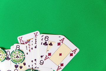 gambling poker chips stack and playing cards on green table. empty space for text and design. top view