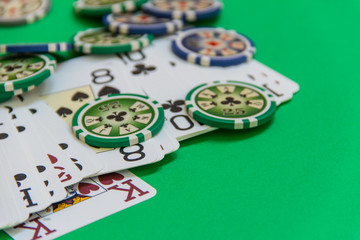 gambling poker chips stack and playing cards on green table. empty space for text and design. closeup