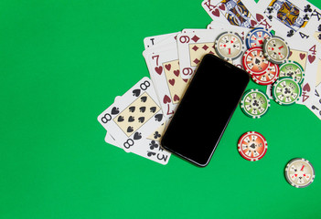 mobile phone and poker chips with playing cards on a green table. online casino concept. top wiev of a porer table. template