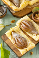 Summer dessert. Homemade Cake Puff Pastry with Pear and Stuffed with Nut Cream a rustic wooden table.