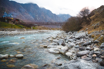 Beautiful pedestrian bridge over the raging mountain river in the Caucasus Mountains. Kabardino...