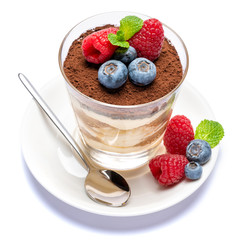 Classic tiramisu dessert with blueberries and raspberries in a glass isolated on a white background with clipping path