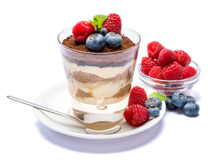 Classic tiramisu dessert with blueberries and raspberries in a glass isolated on a white background with clipping path