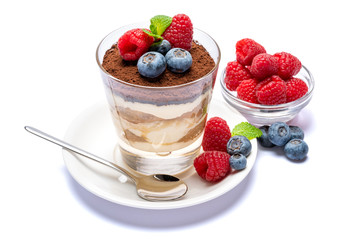 Classic tiramisu dessert with blueberries and raspberries in a glass isolated on a white background with clipping path