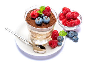 Classic tiramisu dessert with blueberries and raspberries in a glass isolated on a white background with clipping path