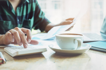 The accountant is pressing the calculator to calculating check the accuracy of the investment budget with using computer laptop and document data to analysis.