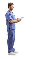 Young male health pratctitioner in a blue uniform writing on a clipboard