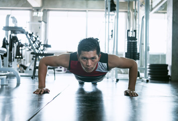 Naklejka na ściany i meble Sport. Young asian athletic man doing push-up muscular exercising in fitness gym.