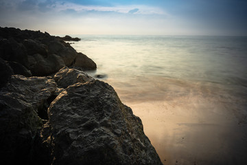beautiful sandy scenic beach in sunset, with rocky breakwater in long exposure in basque country, france, creative background
