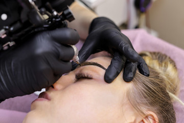 Permanent makeup. Permanent tattooing of eyebrows. Cosmetologist applying permanent make up on eyebrows- eyebrow tattoo