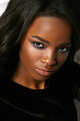 Fototapeta premium Beautiful young black girl seductively looking straight. Portrait of a girl in the studio in a velvet dress.