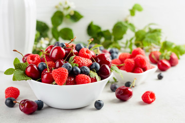 Berries closeup colorful assorted mix of strawberry, blueberry, raspberry and sweet cherry on a white table.
