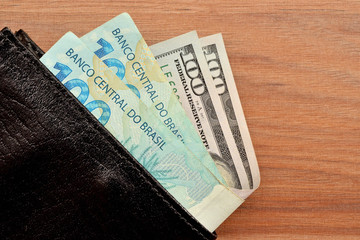 Obraz premium Carteira com notas de 100 reais e 100 dólares para investimento