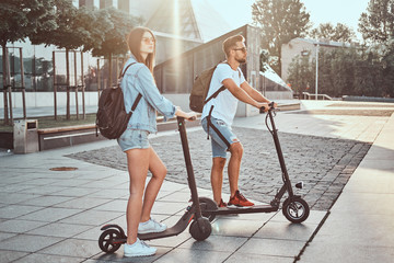 Young attractive couple is enjoying nice summer day while riding their own electro scooters.
