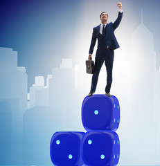 Businessman balancing on top of dice stack in uncertainty concep